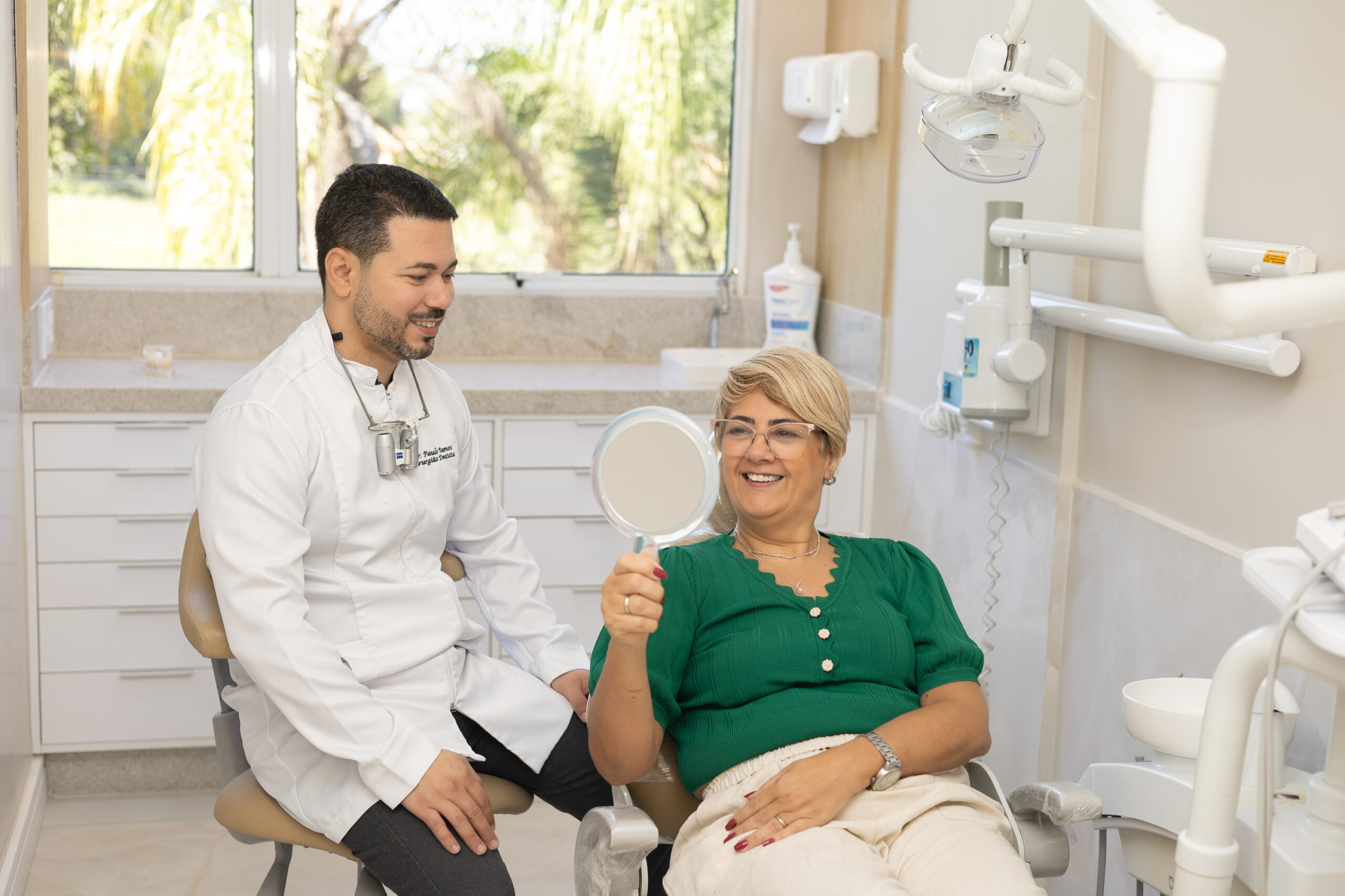 foto do paulo com a dani sorrindo dentista em Vargem Grande RJ, atendendo na sala de atendimento odontologico , com a paciente sorrindo e satisfeita com a protese dentaria